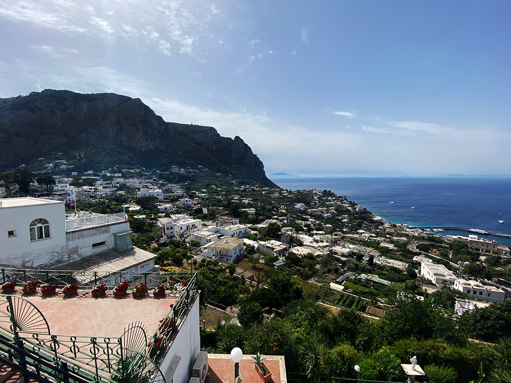 view down from capri town of hillside buildings and sea beyond