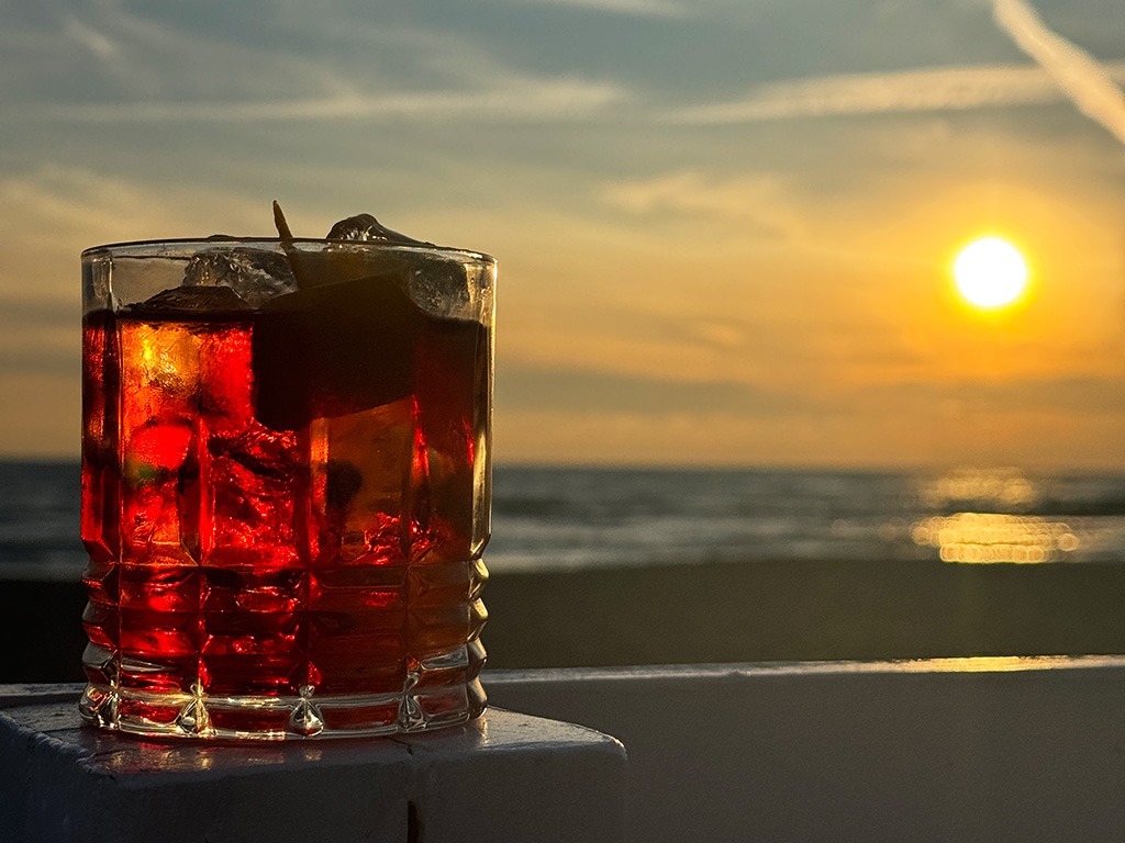 close up of negroni cocktail in a glass at sunset on the beach in ostia