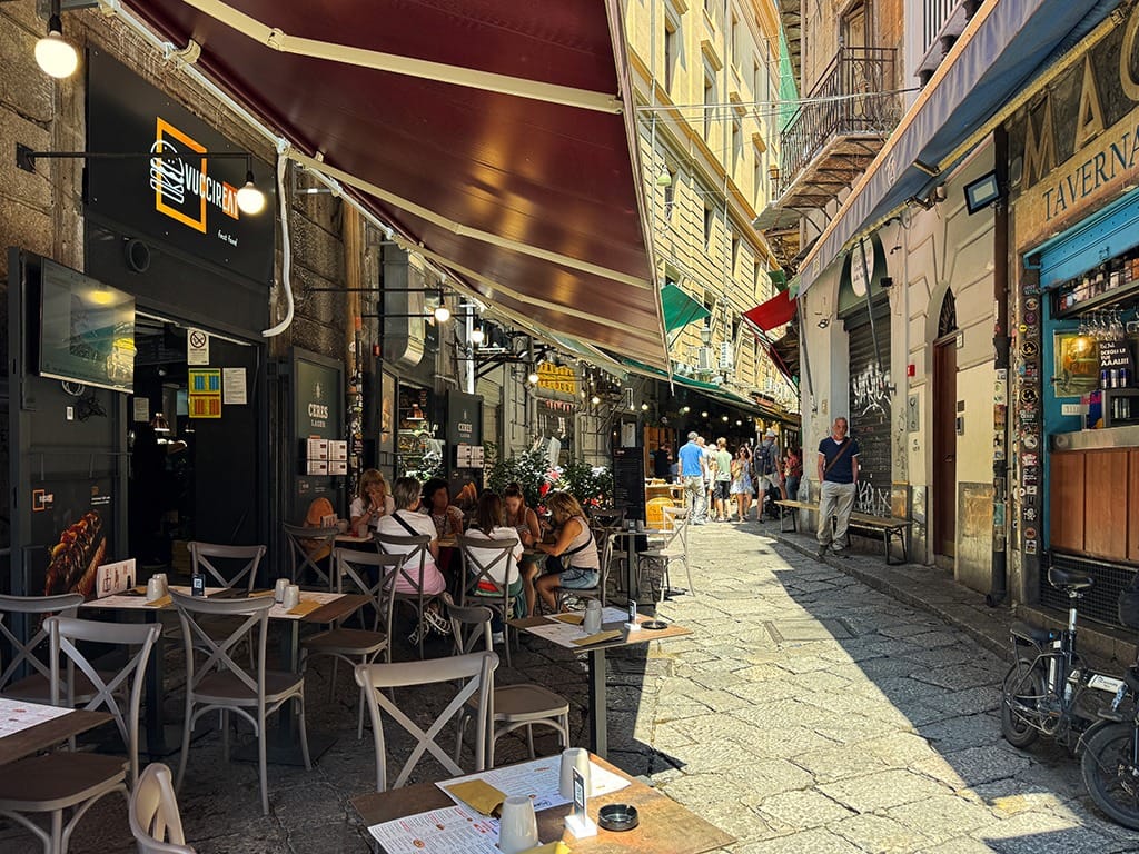 street of vucciria market in palermo with tables and chairs to side