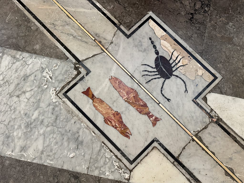 close up of meridian line in palermo cathedral with zodiac signs for scorpio and pisces