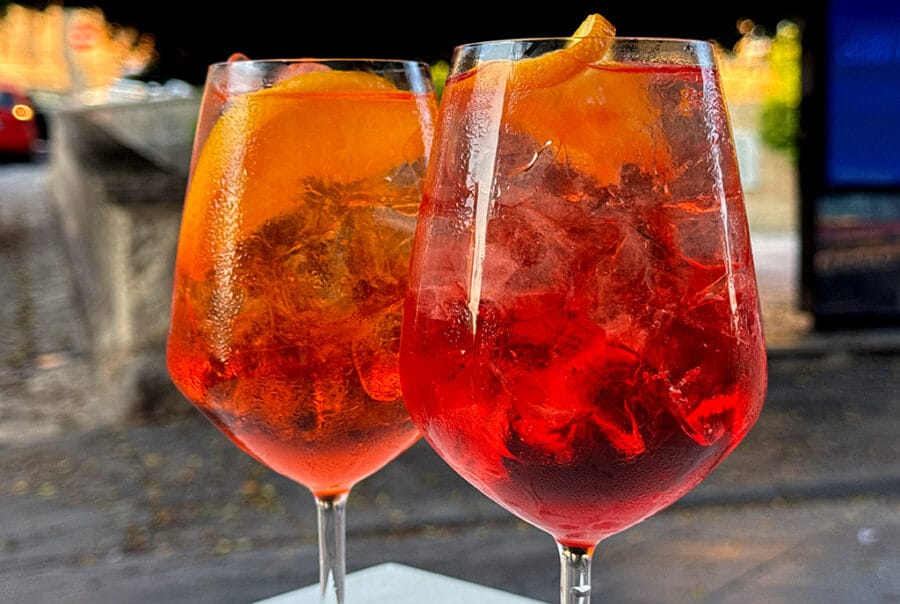 close up of aperol spritz and campari spritz in wine glasses