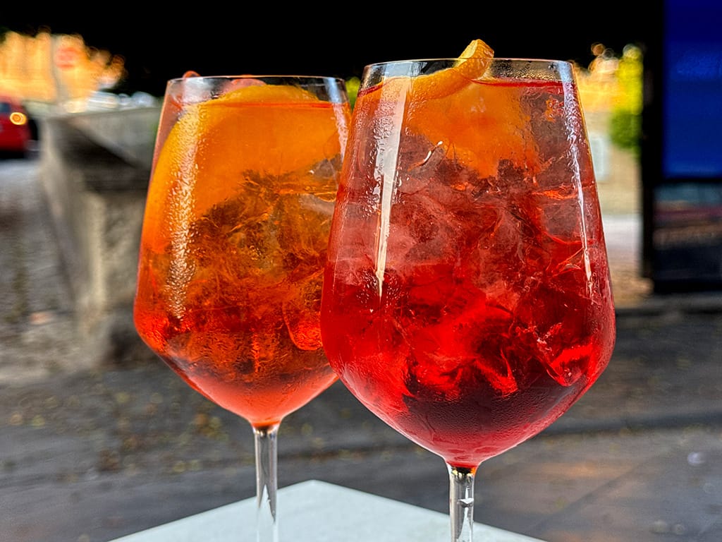 close up of aperol spritz and campari spritz in wine glasses