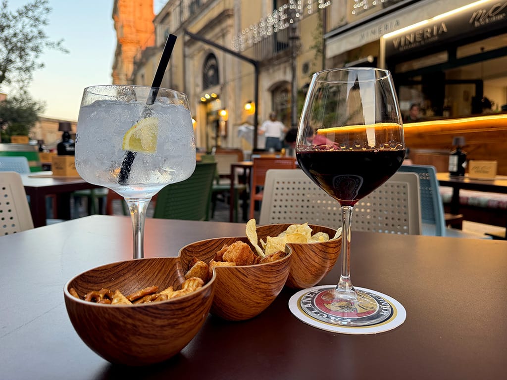 sunset aperitivo with red wine and gin and tonic with wooden snack bowls